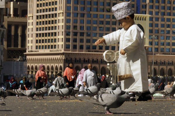 A boy feeds pigeons outside the Grand Mosque in the Muslim holy city of Mecca, Saudi Arabia, Monday, Jan. 27, 2020. (AP Photo/Amr Nabil)