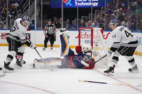 St. Louis Blues goaltender Jordan Binnington, center, stops a shot by Los Angeles Kings' Mikey Anderson (44) as Kings' Alex Laferriere (78) looks for the rebound during the third period of an NHL hockey game Wednesday, March 13, 2024, in St. Louis. (AP Photo/Jeff Roberson)