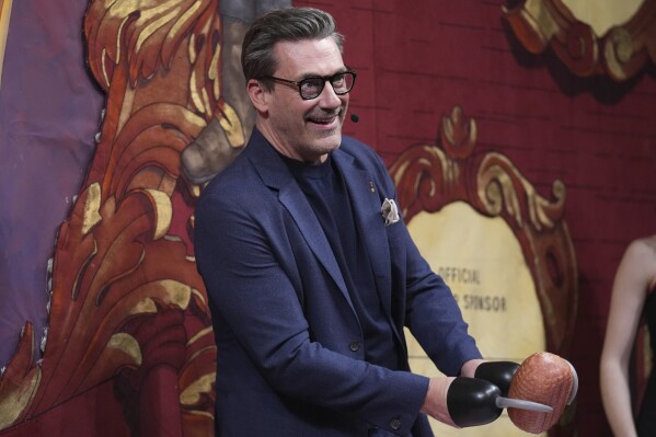 Harvard University's Hasty Pudding Theatricals Man of the Year Jon Hamm holds a ham while being roasted, Friday, Jan. 31, 2025, in Cambridge, Mass. (AP Photo/Charles Krupa)