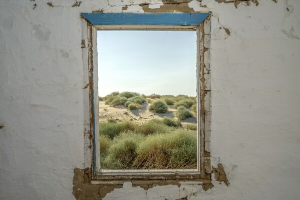 Sand can be seen through the window of an abandoned structure near the dried-up Aral Sea, near Aralsk, Kazakhstan, Monday, July 3, 2023. (AP Photo/Ebrahim Noroozi)