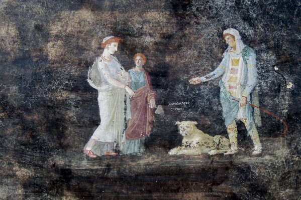 This image released by the Italian Culture Ministry on Wednesday, April 10, 2024, shows a fresco depicting the Greek mythology's figures of Helen, left, and Paris of Troy, right, inside an imposing banquet hall, with elegant black walls, decorated with mythological subjects inspired by the Trojan War, recently unhearted in the Pompeii archaeological area near Naples in southern Italy. (Italian Culture Ministry via AP, HO)