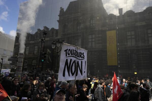 Protesters, one carrying a poster "It's still No" during a demonstration Thursday, April 13, 2023 in Paris. Protesters opposed to President Emmanuel Macron's unpopular plan to raise the retirement age in France marched Thursday in cities and towns around France in a final show of anger before a decision on whether the measure meets constitutional standards. (AP Photo/Thibault Camus)