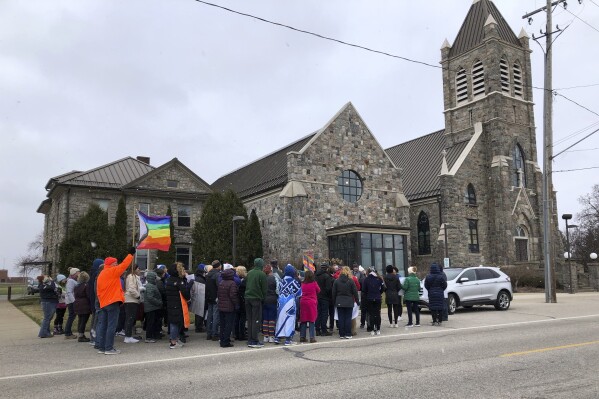 Protesters gather outside St. Joseph the Worker Church on March 17, 2024, in Beal City, Mich., in response to a priest's criticism of a gay author who read a book at a parish school. The Rev. Thomas Held resigned as pastor on April 16, 2024. (Sue Knickerbocker Field/The Morning Sun via AP)