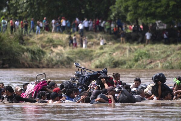 A new group of Central American migrants wade in mass across the Suchiate River, that connects Guatemala and Mexico, in Tecun Uman, Guatemala, Monday, Oct. 29, 2018. The first group was able to cross the river on rafts — an option now blocked by Mexican Navy river and shore patrols. (AP Photo/Santiago Billy)