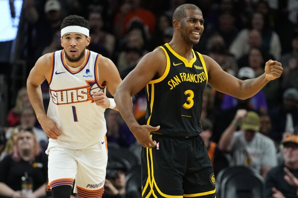 Golden State Warriors guard Chris Paul (3) looks for a call as Phoenix Suns guard Devin Booker runs up court after a basket during the first half of an NBA basketball game, Wednesday, Nov. 22, 2023, in Phoenix. (AP Photo/Matt York)