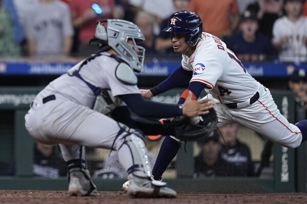 Houston Astros' Mauricio Dubon is tagged out at the plate by New York Yankees catcher Jose Trevino during the ninth inning of a baseball game, Thursday, March 28, 2024, in Houston. (AP Photo/Kevin M. Cox)
