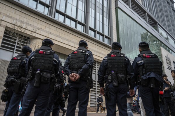 Police officers stand guard outside West Kowloon Magistrates' Courts, where activist publisher Jimmy Lai's trial is scheduled to open, in Hong Kong, Monday, Dec. 18, 2023. A landmark national security trial opened Monday in Hong Kong for prominent activist publisher Jimmy Lai, who faces a possible life sentence if convicted under a law imposed by Beijing to crush dissidents. (AP Photo/Vernon Yuen)