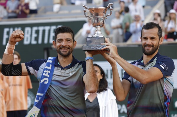 Marcelo Arevalo, of El Salvador, and Mate Pavic of Croatia celebrate with the trophy as they won the men's doubles final match of the French Open tennis tournament against Italy's Simone Bolelli and Andrea Vavassori at the Roland Garros stadium in Paris, France, Saturday, June 8, 2024. (AP Photo/Jean-Francois Badias)