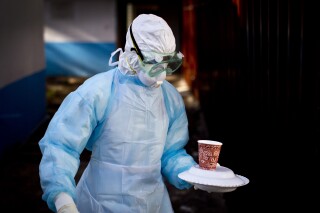 In this Oct. 8, 2014 photo, a medical worker from the Infection Prevention and Control unit wearing full protective equipment carries a meal to an isolation tent housing a man being quarantined after coming into contact in Uganda with a carrier of the Marburg Virus, at the Kenyatta National Hospital in Nairobi, Kenya. (AP Photo/Ben Curtis, File)
