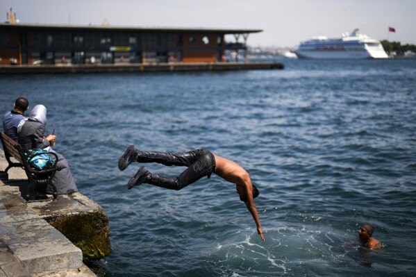 Youngster dive into the Bosphorus next to Karakoy ferry terminal on a hot summer day in Istanbul, Turkey, Thursday, July 6, 2023. (AP Photo/Francisco Seco)