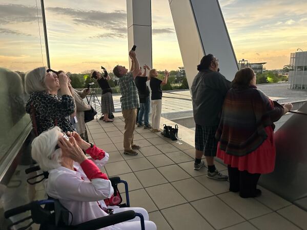 Crowds gathered on the balcony of the Clinton presidential library and in the surrounding park cheered as the eclipse reached totality.  (AP Photo/Andrew DeMillo)