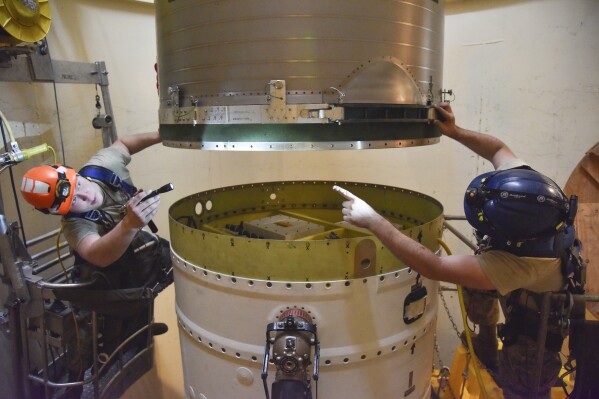 FILE - In this image provided by the U.S. Air Force, Airman 1st Class Jackson Ligon, left, and Senior Airman Jonathan Marinaccio, 341st Missile Maintenance Squadron technicians connect a re-entry system to a spacer on an intercontinental ballistic missile during a Simulated Electronic Launch-Minuteman test Sept. 22, 2020, at a launch facility near Malmstrom Air Force Base in Great Falls, Mont. The Air Force has temporarily closed two nuclear launch facilities after finding unsafe levels of a likely carcinogen in air samples at a Montana missile base where a striking number of men and women who served have reported cancer diagnoses. (Senior Airman Daniel Brosam/U.S. Air Force via AP, File)