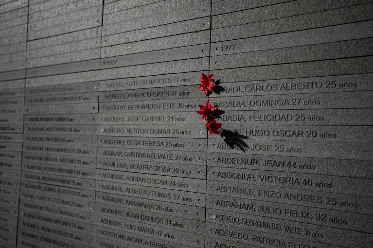 Flowers hang by the names of people who disappeared during Argentina's military dictatorship (1976 - 1983) at Memory Park in Buenos Aires, Argentina, Sunday, Jan. 28, 2024. Human rights organizations report that 30,000 people disappeared during that period. (AP Photo/Natacha Pisarenko)