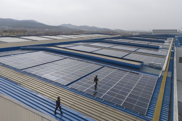 Workers cleaning solar panels work on the rooftop of the factory of energy equipment manufacture Iraeta on the outskirts of Jinan in eastern China's Shandong province on March 21, 2024. It's the leading province for renewable energy capacity, but that also means it's the first to encounter the difficulties of rapid growth. (AP Photo/Ng Han Guan)