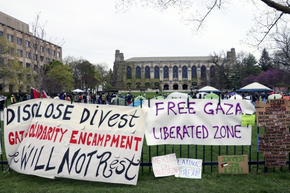 Signs are posted outside a tent encampment at Northwestern University Friday, April 26, 2024, in Evanston, Illinois.  Students want the university to divest from funds linked to Israel or that profit from its war in Gaza.  (AP Photo/Teresa Crawford)