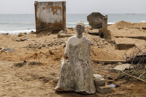 A sculpture of Afeli Bernice Adzo's great-grandfather sits in a family cemetery where remains were exhumed due to coastal erosion in Avegadzi, Ghana, Tuesday, March 4, 2025. (AP Photo/Misper Apawu)