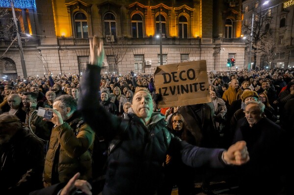 A man throws an egg at the electoral commission building as several thousand Serbian opposition supporters protest in Belgrade, Serbia, Monday, Dec. 18, 2023. An early official vote count of Serbia's weekend election on Monday confirmed victory for the ruling populist party in a parliamentary vote in the Balkan country, but political tensions rose over reported irregularities in the capital, Belgrade. Banner reads 
