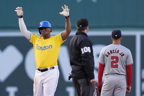 Boston Red Sox's Rafael Devers, left, celebrates after his two-run double as Washington Nationals second baseman Luis García Jr. (2) looks to the outfield during the eighth inning of a baseball game, Saturday, May 11, 2024, in Boston. (AP Photo/Michael Dwyer)