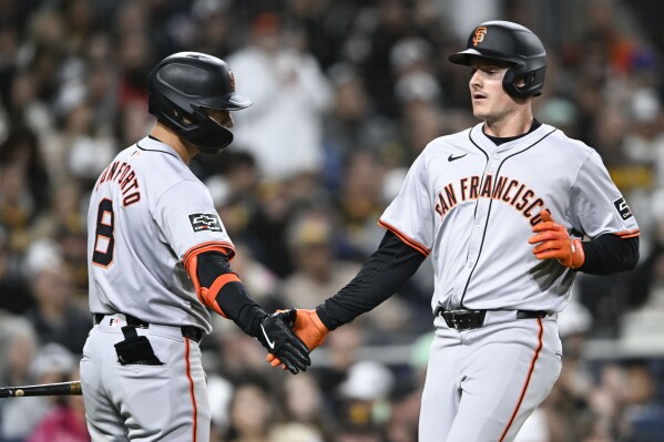San Francisco Giants' Matt Chapman, right, is congratulated by Michael Conforto (8) after he scored against the San Diego Padres during the seventh inning of a baseball game Friday, March 29, 2024, in San Diego. (AP Photo/Denis Poroy)