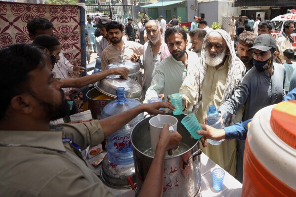 Voluntarios ofrecen agua con lima y azúcar a la gente en un campamento habilitado para evitar golpes de calor en un caluroso día de verano en Karachi, Pakistán, el jueves 23 de mayo de 2024. Los médicos atendían a cientos de victimas de golpes de calor en varios hospitales del país tras el inicio de un intenso episodio de altas temperaturas. (AP Foto/Fareed Khan)