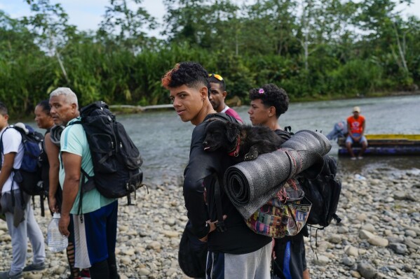 Alejando Colmenares, from Venezuela, carries his dog on his back as he lines up with other migrants to take a boat in Bajo Chiquito, Darien province, Panama, Thursday, Oct. 5, 2023, after walking across the Darien Gap from Colombia. (AP Photo/Arnulfo Franco)