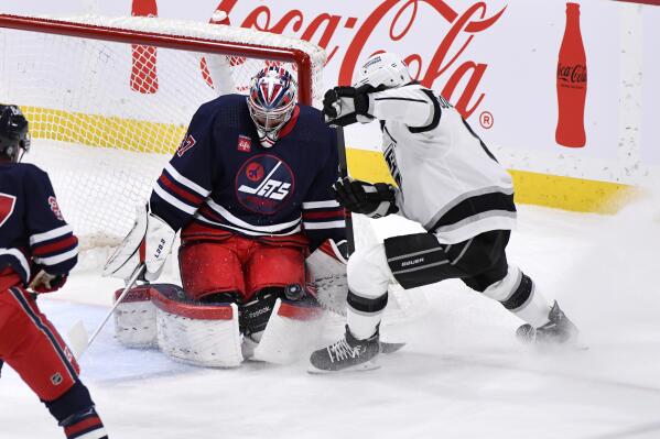 Winnipeg Jets goaltender Connor Hellebuyck (37) makes a save on Los Angeles Kings' Drew Doughty (8) during the first period of an NHL hockey game in Winnipeg, Manitoba, on Tuesday, Feb. 28, 2023. (Fred Greenslade/The Canadian Press via AP)