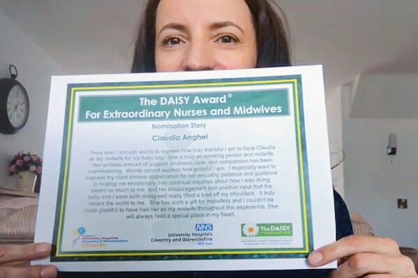 In this image taken from an online video interview with The Associated Press, Claudia Anghel, a Romanian midwife working in England, shows her nomination for the Daisy Award, in Nuneaton, England, Tuesday, July, 28, 2020. Anghel's success story as one of 600,000 Romanians in Britain is at the same time a telling sign of how the deficiencies of her home country's health care system and the bleak prospects for a better future for herself and her family have left huge gaps in Romanian society and its health care system. (AP Photo)
