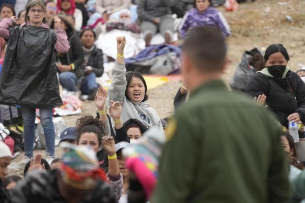 Women hold their wristbands high in the hope they are chosen by U.S. Border Patrol agents to be taken to processing after waiting for days between two border walls to apply for asylum Friday, May 12, 2023, in San Diego. The border between the U.S. and Mexico was relatively calm Friday, offering few signs of the chaos that had been feared following a rush by worried migrants to enter the U.S. before the end of pandemic-related immigration restrictions. (AP Photo/Gregory Bull)