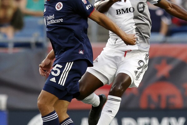 Toronto FC's C.J. Sapong (9) heads the ball next to New England Revolution's Brandon Bye (15) during the first half of an MLS soccer match Saturday, June 24, 2023, in Foxborough, Mass. (AP Photo/Michael Dwyer)