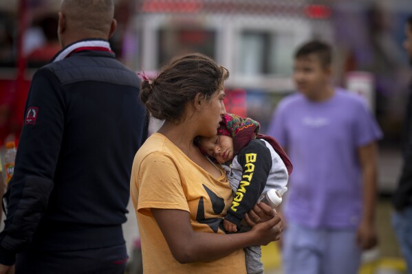 A baby sleeps in a young woman's arms at a fair in Hagioaica, Romania, Saturday, Sept. 16, 2023. For many families in poorer areas of the country, Romania's autumn fairs, like the Titu Fair, are one of the very few still affordable entertainment events of the year. (AP Photo/Andreea Alexandru)