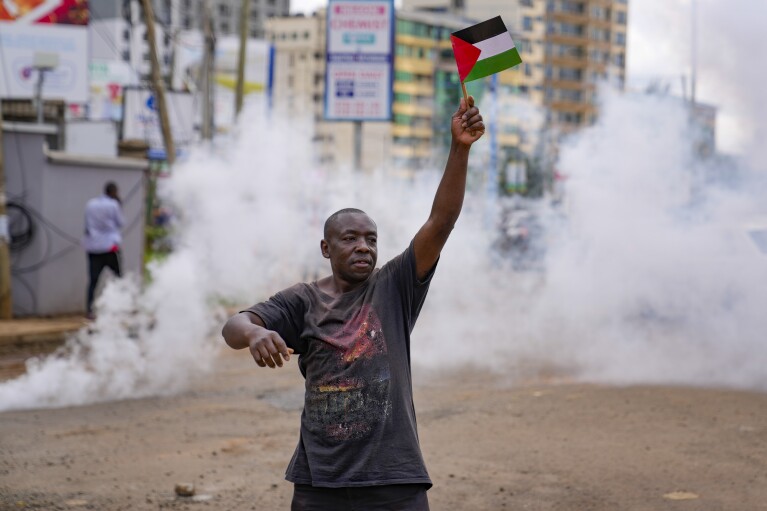 FILE - A demonstrator waves a Palestinian flag as Kenyan police officers fire teargas canisters during a protest against Israel and in support of Palestinians, in Nairobi, Kenya Nov. 9, 2023. (AP Photo/Brian Inganga, File)