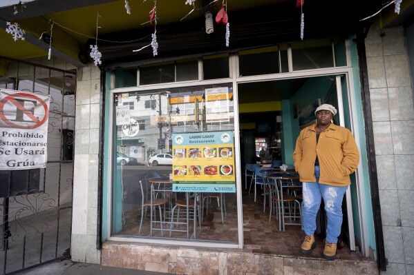 Vivianne Petit Frere, of Haiti, stands in the doorway of the Haitian restaurant she runs, Wednesday, March 13, 2024, in downtown Tijuana, Mexico. When she fled to Brazil in 2019, walked through Panamanian jungle two years later, met her husband in Mexico and opened the restaurant, Petit Frere always felt she would eventually return home. Until now. (AP Photo/Gregory Bull)