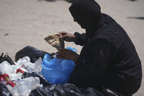In a sign of growing desperation, Islam Abu Taeima, a 40-year-old mother of five, grabs a piece of bread from a pile of garbage in Gaza City, Sunday, May 25, 2025.(AP Photo/(AP Photo/Jehad Alshrafi)