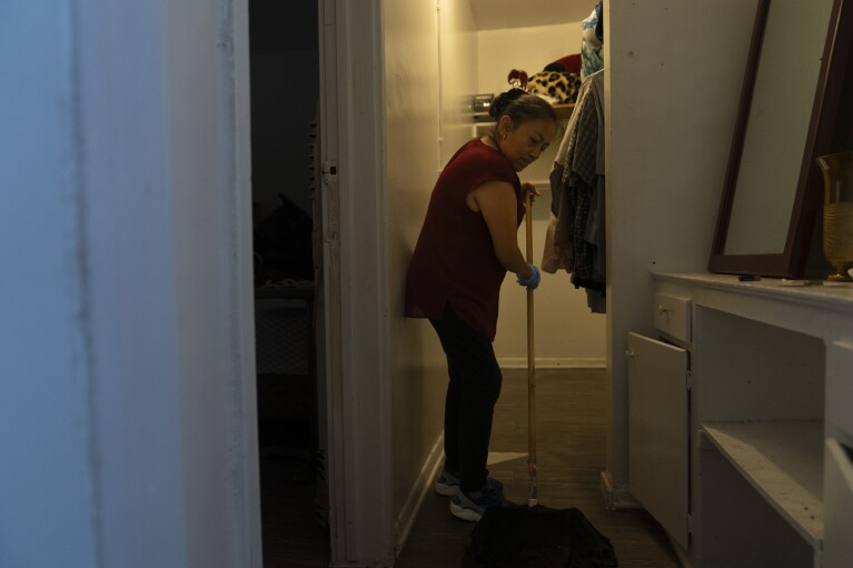 Deneffy Sánchez's mother, Lilian Lopez, cleans a walk-in closet where one of her family's roommates used to sleep in before moving out, in Los Angeles, Saturday, Sept. 9, 2023. In Los Angeles, more than 13,000 students are homeless, according to the city's superintendent. Only around 2,000 of them live in shelters. (AP Photo/Jae C. Hong)