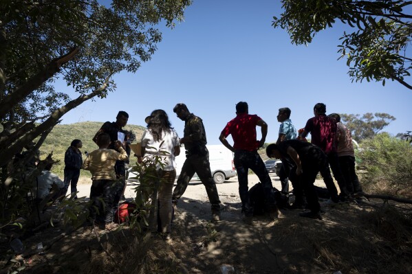 Border Patrol agents talk with migrants seeking asylum as they prepare them for transportation to be processed, Wednesday, June 5, 2024, near Dulzura, Calif. President Joe Biden on Tuesday unveiled plans to enact immediate significant restrictions on migrants seeking asylum at the U.S.-Mexico border as the White House tries to neutralize immigration as a political liability ahead of the November elections. (AP Photo/Gregory Bull)