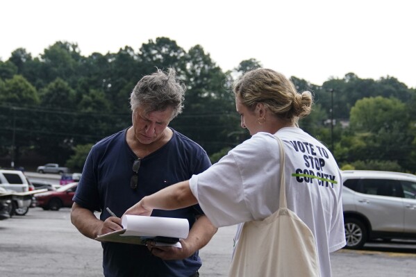 FILE - Canvasser Sienna Giraldi, 26, right, with Stop Cop City Vote Coalition, talks to an Atlanta resident, left, Thursday, July 20, 2023, in Atlanta. Georgia activists are furious that Democratic senators haven’t condemned Atlanta officials’ plan to verify every signature on a petition to force a vote on a proposed police and firefighting training center. (AP Photo/Brynn Anderson, File)