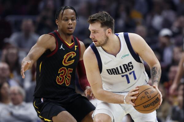 Dallas Mavericks guard Luka Doncic (77) is defended by Cleveland Cavaliers guard Isaac Okoro (35) during the first half of an NBA basketball game Wednesday, March 30, 2022, in Cleveland. (AP Photo/Ron Schwane)