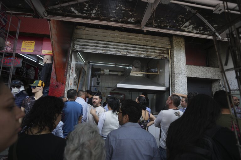 Los clientes hacen fila para pedir tacos en el puesto de Tacos El Califa de León, en la Ciudad de México, el miércoles 15 de mayo de 2024. Tacos El Califa de León es el primer puesto de tacos en recibir una estrella Michelin de la guía gastronómica francesa.  (Foto AP/Fernando Llano)