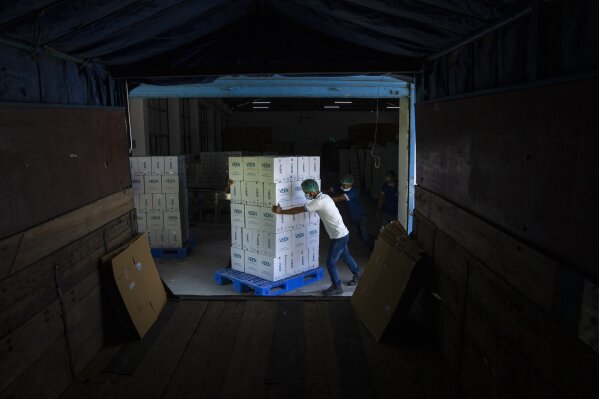 Workers push a trolley loaded with cartons of Veen mineral water before loading it into a truck inside a bottling plant near Samtse, Bhutan, Wednesday, May 10, 2023. Veen brings about 20,000 cases or 240,000 bottles into India, according to company officials. The water, mostly sold in luxury Indian hotels and restaurants, comes from a spring near the bottling plant. (AP Photo/Dar Yasin)