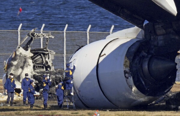 ARCHIVO - La policía investiga los restos de un avión de Japan Airlines en el aeropuerto Haneda de Tokio el 4 de enero de 2024 en Tokio, Japón.  Los 379 pasajeros a bordo del vuelo JAL-516 de Japan Airlines no esperaban que su avión se incendiara cuando estaba a punto de aterrizar en el aeropuerto Haneda de Tokio el martes por la noche.  Un avión más pequeño Bombardier Dash-8 de la Guardia Costera, que se preparaba para despegar para entregar ayuda de emergencia al centro de Japón afectado por el terremoto, estaba usando la misma pista cuando los dos aviones chocaron.  The Associated Press recopiló relatos de testigos, funcionarios y transcripciones de comunicaciones de control de tráfico.  (Kyodo News vía AP, Archivo)