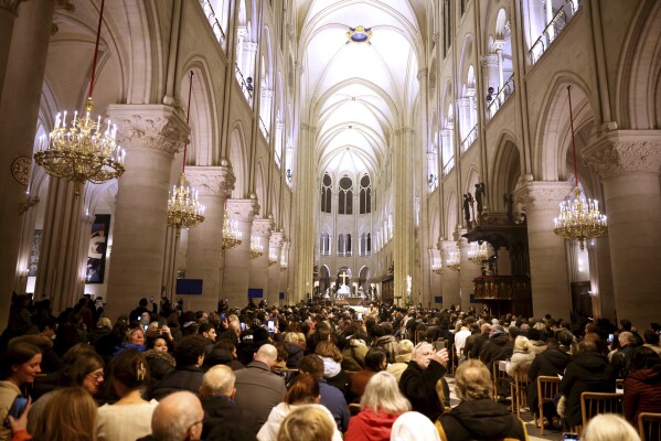 Faithful sit before the mass at Notre Dame Cathedral as the monuments hosts Christmas Eve services for the first time since a devastating 2019 fire, Tuesday, Dec. 24, 2024 in Paris. (AP Photo/Thomas Padilla)