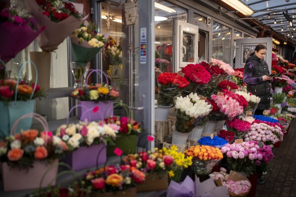 A vendor uses a phone as she waits for customers at a flower shop on Valentine's Day in Vilnius, Lithuania, Wednesday, Feb. 14, 2024. (AP Photo/Mindaugas Kulbis)