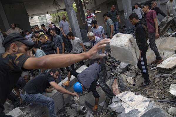 Palestinians look for survivors in a building destroyed in an Israeli bombardment in Rafah refugee camp in Gaza Strip on Tuesday, Oct. 17, 2023. (AP Photo/Fatima Shbair)