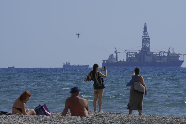 FILE - People on the beach take photos of the 'Tungsten Explored' drilling ship, in the southern coastal city of Larnaca, Cyprus, on Nov. 3, 2021. The Cyprus government and U.S. energy company Chevron have reached a deal on how to develop the Aphrodite gas field, the first to be discovered under the seafloor off Cyprus, an official said Friday, Dec. 1, 2023. The field is estimated to hold 4.2 trillion cubic feet of gas. (AP Photo/Petros Karadjias, File)