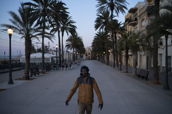 Thierno, from Senegal, walks to work on an empty street as the lockdown to combat the spread of coronavirus continues in Badalona, Spain, Friday, March 27, 2020. The new coronavirus causes mild or moderate symptoms for most people, but for some, especially older adults and people with existing health problems, it can cause more severe illness or death. (AP Photo/Felipe Dana)