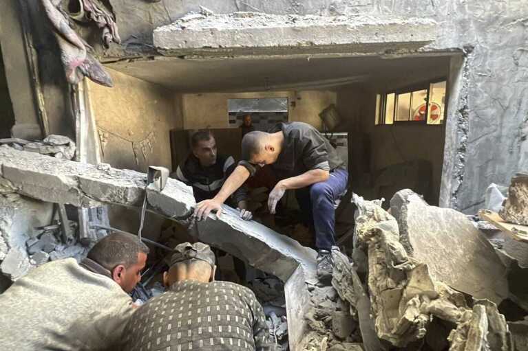 People look through the rubble of a home destroyed by an Israeli airstrike on Dec. 6, 2023, in Nuseirat refugee camp in the Gaza Strip. Four-year-old Omar Abu Kawaik was pulled alive from the rubble and brought out of Gaza then flown to the United States, where he received treatment including a prosthetic arm. (Courtesy of Maha Abu Kuwaik via AP)