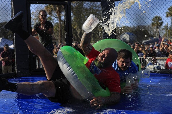 Jon Davis, left, loses his footing and most of his beer against Gary "Doughboy" Anderson, both of Jacksonville, in the "Florida Sumo" competition during the inaugural Florida Man Games, Saturday, Feb. 24, 2024, at Francis Field in St. Augustine, Fla. Hundreds turned out to witness the Floridian Olympic-style events. Team "Hanky Spanky," based out of St. Augustine, would take home the championship belt. (Corey Perrine/The Florida Times-Union via AP)