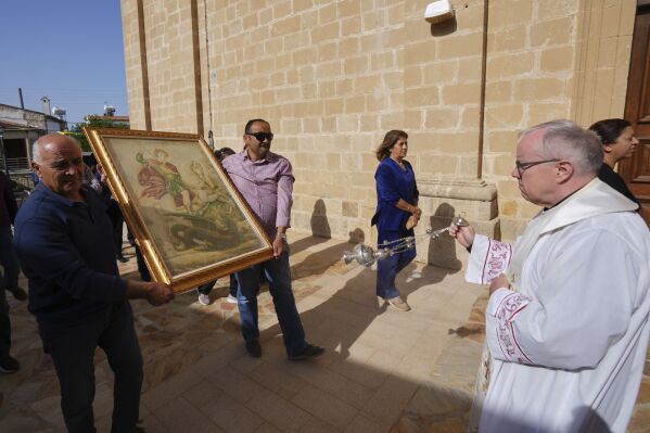 A priest swings a senser at an icon of St. George during a traditional procession on the saint's Feast Day outside St. George Church in the Maronite village of Kormakitis in the breakaway north of the ethnically divided Cyprus on Wednesday, April 23, 2025. (AP Photo/Petros Karadjias)