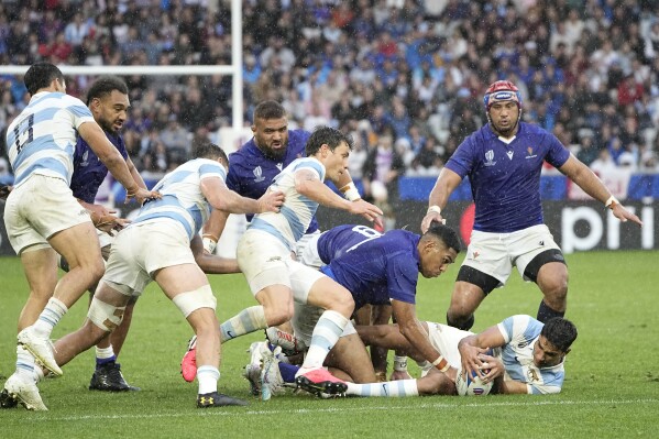 Argentina's Santiago Carreras, bottom, is tackled by Samoa's Nigel Ah Wong during the Rugby World Cup Pool D match between Argentina and Samoa at the Stade Geoffroy Guichard in Saint-Etienne, France, Friday, Sept. 22, 2023. (AP Photo/Laurent Cipriani)