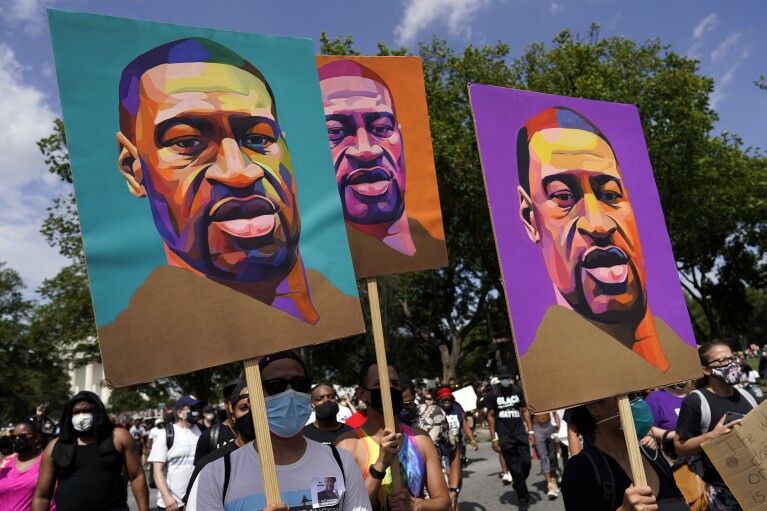 FILE - People carry signs with George Floyd's portrait as they march from the Lincoln Memorial to the Martin Luther King Jr. Memorial in Washington on Aug. 28, 2020. (AP Photo/Carolyn Kaster, File)
